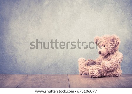 Retro Teddy Bear toy sitting alone front old textured concrete wall background. Vintage instagram style filtered photo
