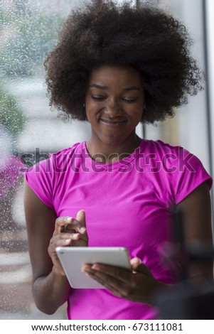 beautiful african american woman using tablet computer from home while rain and bad weather is outdoor