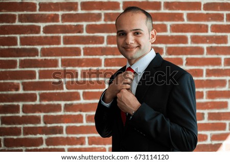 handsome man, businessman in a black business suit standing near brick wall