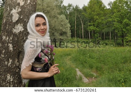 Portrait of a young beautiful girl near a birch in the forest with clover