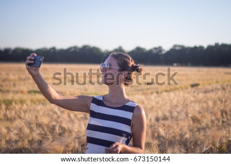 Young woman in dress make photo with cellphone in fields