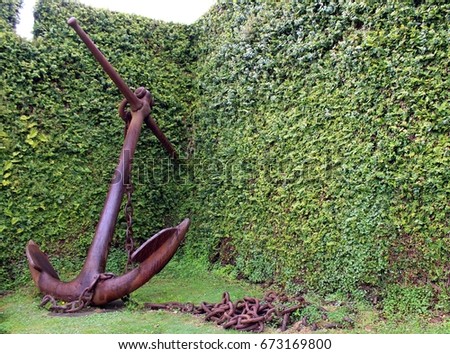 Old iron anchor on a green grass background