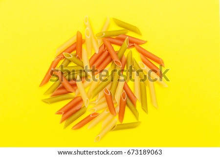 Bunch of colorful macaroni on yellow background, bunch of pasta of different colors