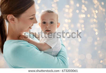 family, motherhood and parenthood concept - close up of happy smiling young mother with little baby over lights background