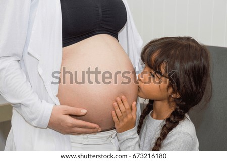 The girl is listening to belly of pregnant  mother