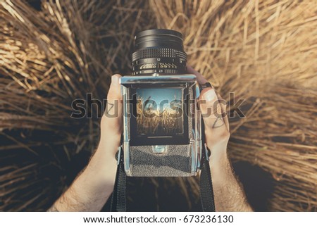 Top view on hands holding retro rustic medium format camera. Mockup with amazing landscape