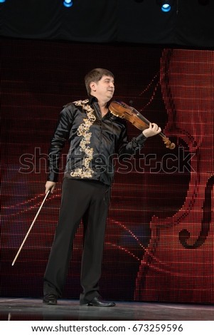 Male artist musician plays the violin on stage