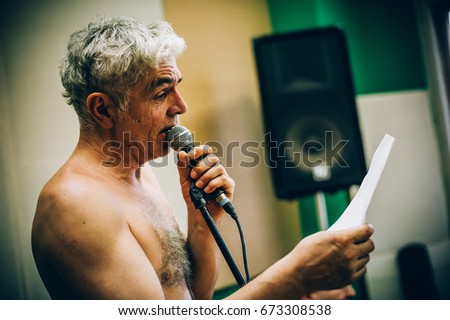 Behind the scene. Famous alternative male singer practice singing on the microphone in the messy recording music studio. Musician live singing