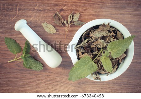 Vintage photo, Fresh natural green and dried lemon balm with white mortar on rustic board, concept of healthy lifestyle, herbalism and alternative medicine