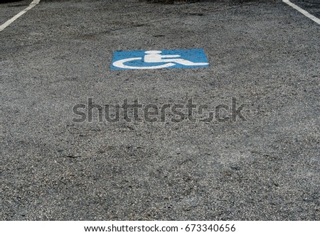 Handicapped sign on the asphalt road in car park