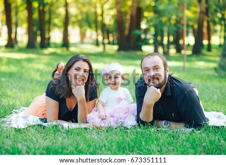 Happiness and harmony in family life. Happy family concept. A young mother and father relaxing in the Park on the grass.