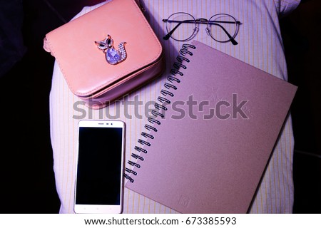 Top view.Business (school) Dairy accessories (blank notepad , mobile phone,glasses,Handbag ) on a yellow background, Vintage instagram style filtered photo