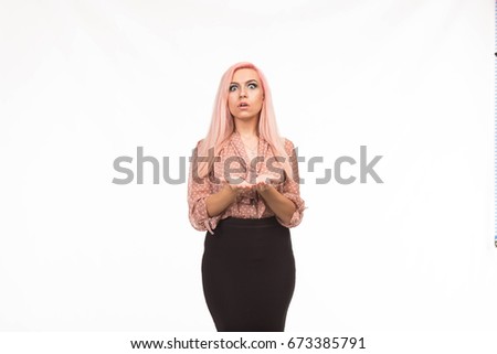 Young surprised woman showing by hands on a gray background. Ideal for banners, registration forms, presentation, landings, presenting concept.