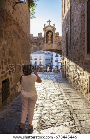 Tourist taking pictures close to Star Arch or Arco de la Estrella, Caceres. Sunset light