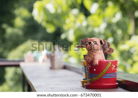 Close up ceramic bull dog in red pot on wooden table with blurred nature background 