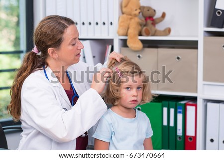 female pediatrician in white lab coat examined little girl for lice