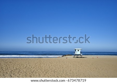 Seascape of pacific ocean, sand and waves; California beach; lifeguard station #7 in faded blue	