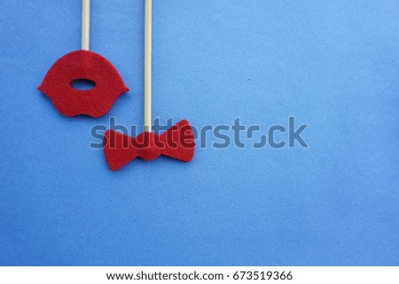 Top or flat lay view of Photo booth props a red lips bow tie on a blue background flat lay. Birthday parties and weddings.