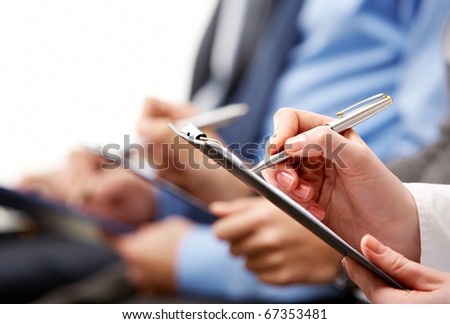 Close-up of human hand holding pen over business document
