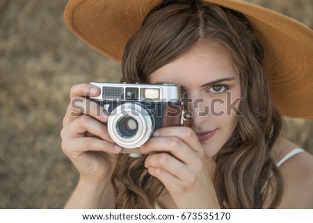 Close up of beautiful, young woman taking photo with vintage camera