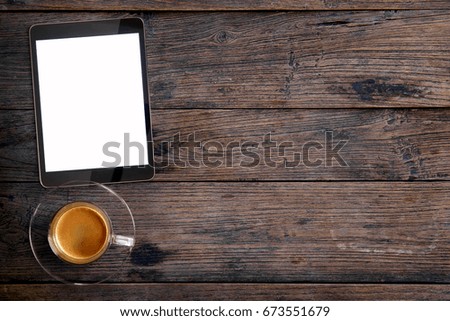 tablet computer and coffee cup on grunge wooden background. Blank screen tablet for graphic display montage.
