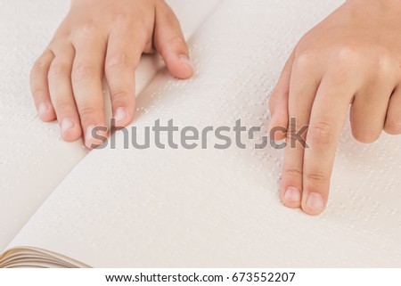 The blind boy is reading a book written on Braille. Touch your finger on the braille code.