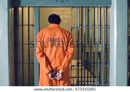 Handcuffed prisoner in jail Royalty-Free Stock Photo #673565005