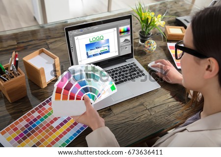 A Woman Holding Color Swatches Using A Laptop With Logo Design Software On The Screen