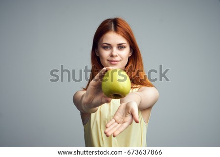 Beautiful young woman on a gray background holding an apple.