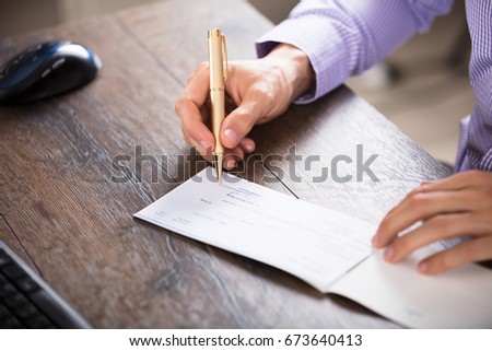 Close-up Of A Businessperson's Hand Signing Cheque In Office Royalty-Free Stock Photo #673640413
