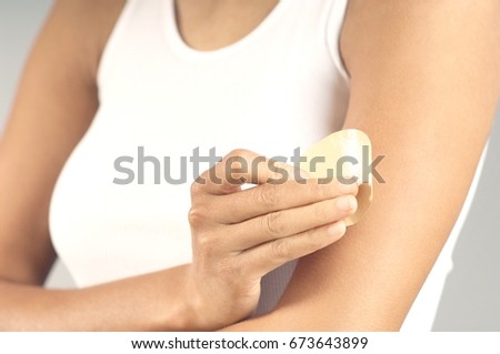 Woman applying patch to arm, mid section Royalty-Free Stock Photo #673643899