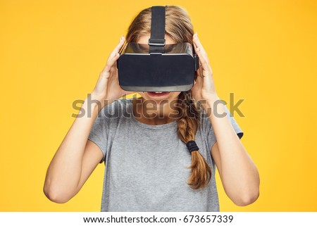 Beautiful young woman on a yellow background with virtual reality glasses.