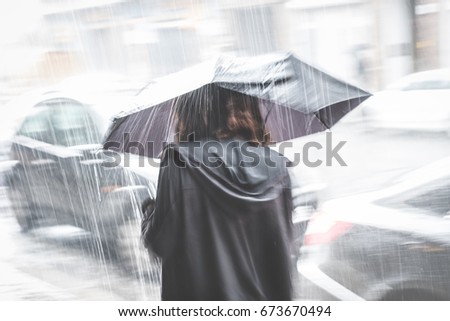 girl with umbrella on street in rain - motion blur