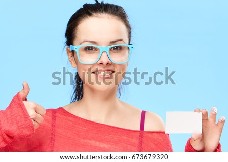 Beautiful young woman on a blue background holds a business card.