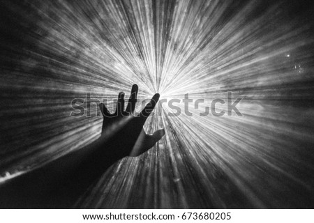 Hand reaches out to touch the light Royalty-Free Stock Photo #673680205