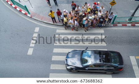 The process of blur people walking in the crosswalk business street city at the rush hour with car on the road (Aerial photo, top view)