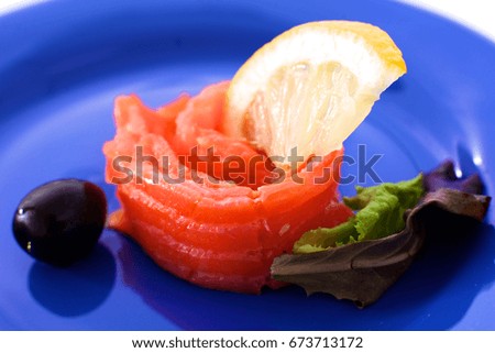 Slice of salmon with lemons and olives on a plate