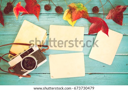 Retro camera and empty old instant paper photo album on wood table with maple leaves in autumn border design - concept of remembrance and nostalgia in fall season. vintage rustic style