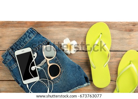 Summer vacation concept. Wooden board with mobile phone and beach accessories on light background