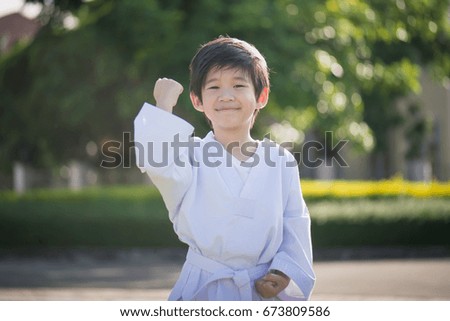 Cute Asian child in white kimono during training karate in summer outdoors