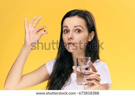 Woman with a pill and a glass of water                               