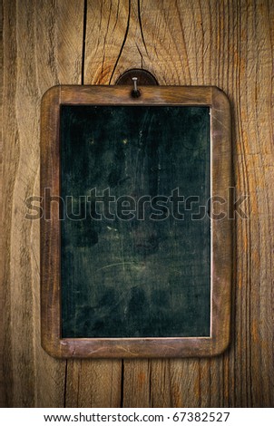 dirty and scratched wooden school slate over a wood wall, vertical image