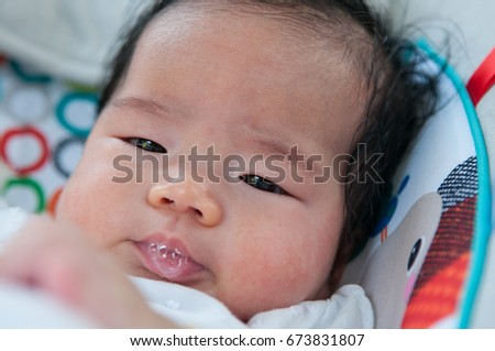 Focus at Asian newborn baby girl is playing with her saliva when she is sleeping on the bed.