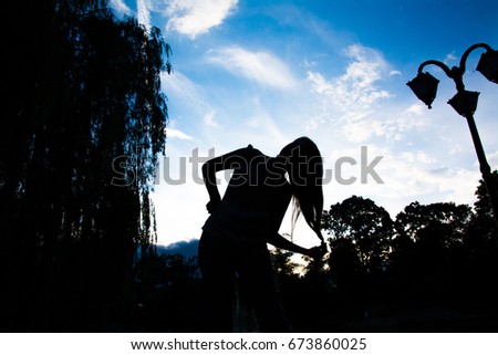 Silhouette of a girl against a blue sky playing with her hair.