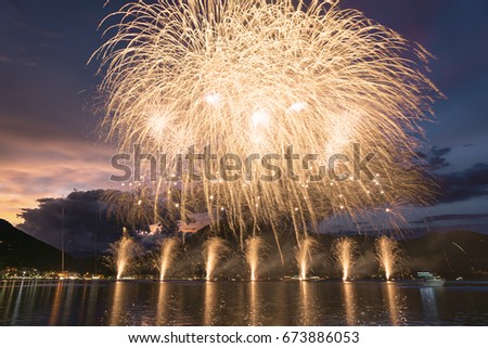 Fireworks on the Lugano Lake in a summer evening with cloudy sky at the sunset in the background