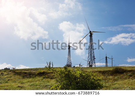 Picture of group of modern windmills for clean energy production. Vast green meadow with windmill turbines producing electrical power. Environment, renewable electric energy and technologies