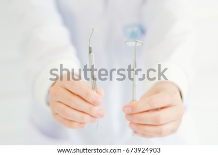 Close up of dentist's hands holding dental tools