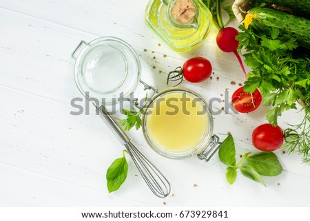 Homemade salad dressing vinaigrette with mustard and olive oil on a white kitchen wooden table. Top view with copy space. Royalty-Free Stock Photo #673929841