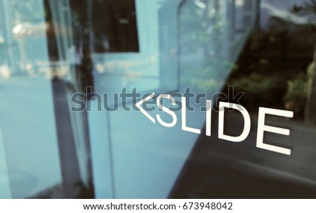 White text of Slide and arrow to open in left side on glass door