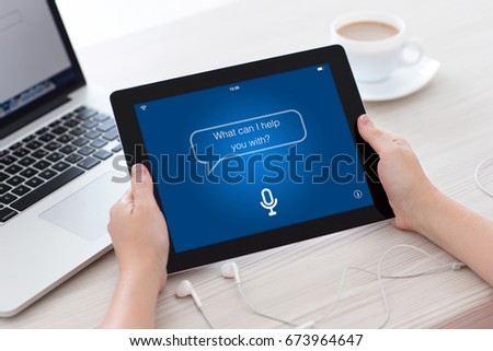 female hands holding tablet with app personal assistant screen laptop and headphones Royalty-Free Stock Photo #673964647